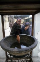 Photo: Norbert Schiller, pilgrims touch the water inside a large granite bowl that the Virgin Mary is said to have baked bread in. The bowl sits in the church courtyard at Samannud and pilgrims come to this site to get blessings from a number of objects, including the bowl.