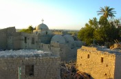 Photo: Paul Perry, a view of the two historical Coptic Orthodox Churches at Dayr al-Maymun located amidst fields and farmers’ houses. To the left is the Church of St. Anthony the Great (251-356) and to the right is the Church of Abu Sefein. In the Church of St. Anthony is the cave where St. Anthony the founder of monasticism, had lived for some 20 years. According to tradition he worshipped in the Church of Abu Sefein.